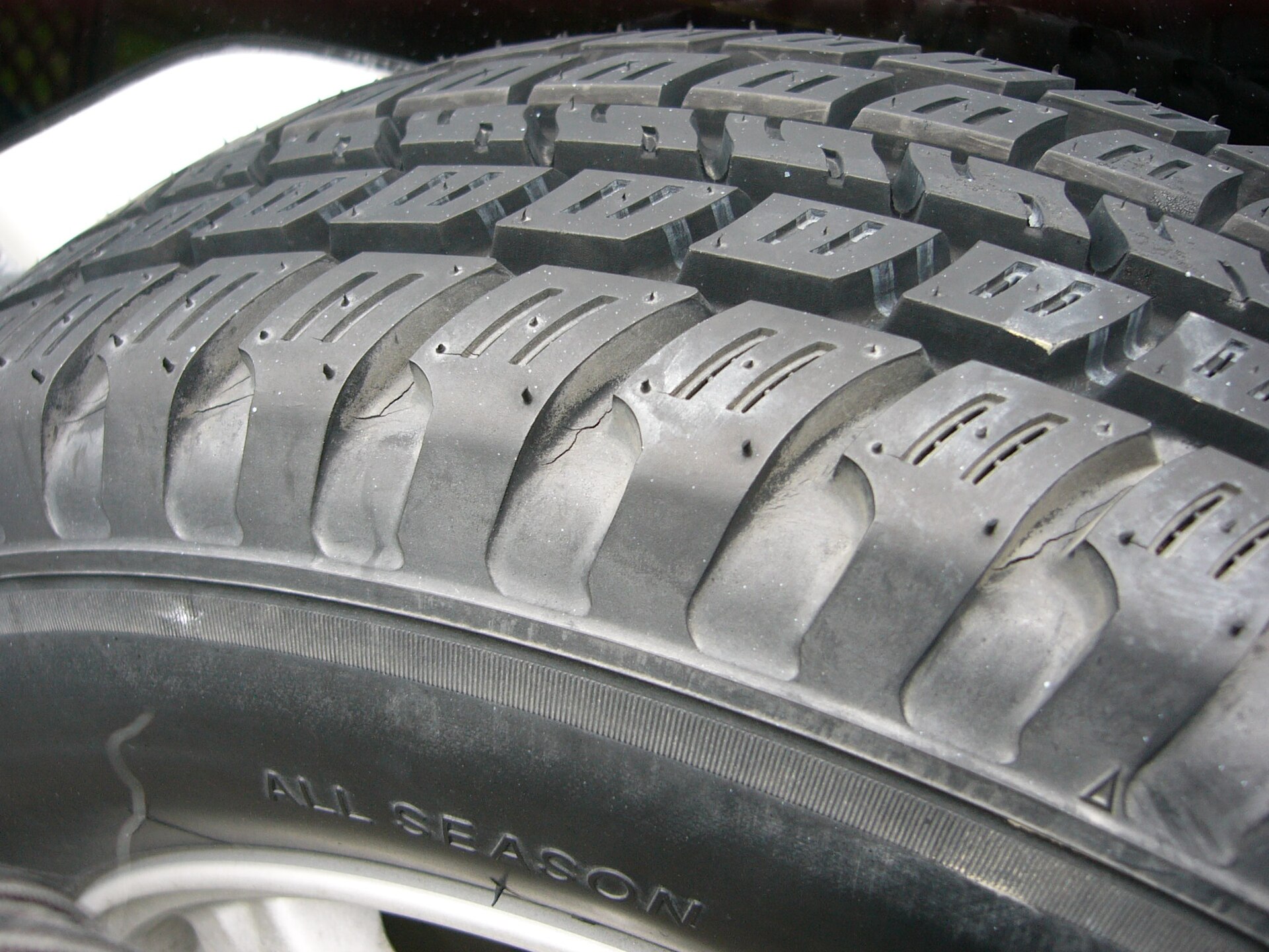 Close-up of an all-season tire, its tread blocks and the words All Season moulded into the sidewall
